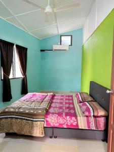 een bed in een kamer met blauwe en groene muren bij HOMESTAY WARISAN BENTONG in Bentong