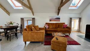 a living room with two couches and a table at Charming Countryside Barn - Cambrian Cottages in Pencader