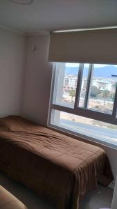 um quarto com uma cama e uma grande janela em departamento frente a la playa herradura em Coquimbo