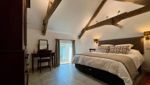 a bedroom with a bed and a table and a window at Charming Countryside Barn - Cambrian Cottages in Pencader