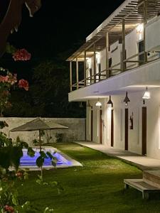 a house with an umbrella and a swimming pool at night at Pousada Mali in Canoa Quebrada