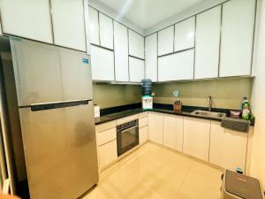 a kitchen with white cabinets and a stainless steel refrigerator at 4 Bedrooms Big Holiday House with Pool by PlayHouse at Batam Center in Batam Center