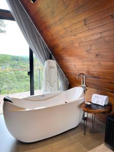 a bath tub in a bathroom with a wooden wall at Pousada Cabanas Araxá in Urubici +17 photos