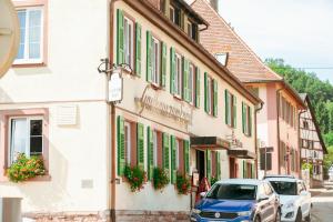 um carro azul estacionado em frente a um edifício com persianas verdes em RISA Hotel Village - Engel & Kreuz em Gaggenau