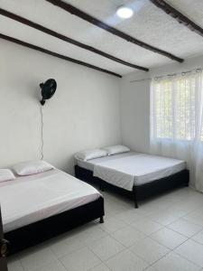 two beds in a room with white walls at Jerusalén in Mariquita