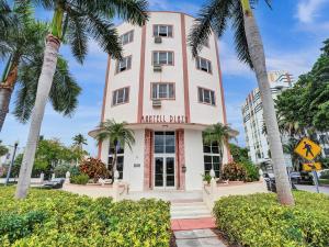 a pink building with palm trees in front of it at Mantell Plaza Apartments in Miami Beach