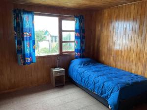 - une chambre avec un lit doté de draps bleus et une fenêtre dans l'établissement Casa vista canal Dalcahue, à Dalcahue