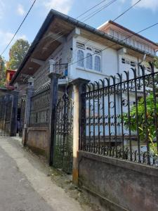 a fence in front of a white house at ShivaPuri Homestay in Darjeeling