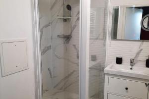 a white bathroom with a shower and a sink at Magnifique appartement avec terrasse et parking, 8 Personnes in Nanterre