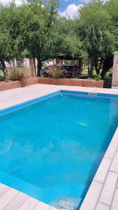 a blue swimming pool with trees in the background at Cabaña Yerba Buena in Carpintería