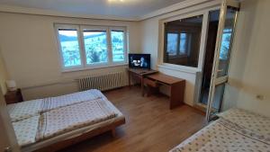 a room with two beds and a desk with a television at ubytovanie v súkromí červenka in Liptovská Teplička
