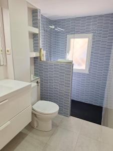 ein Bad mit einem WC und einer blau gefliesten Wand in der Unterkunft Apartamento cercano a IFEMA, Aeropuerto, Clinica Universitaria Navarra y Civitas Metropolitano in Madrid