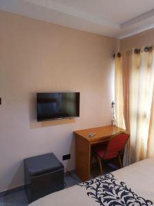 a hotel room with a desk and a television on the wall at Dopad Hills Hotel and Suites in Ojo