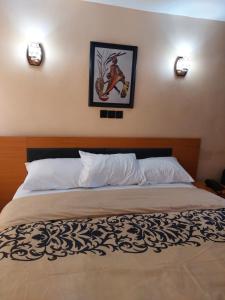 a bed in a bedroom with a picture on the wall at Dopad Hills Hotel and Suites in Ojo