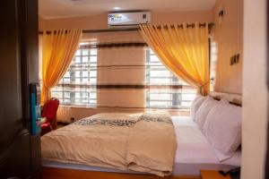 a bedroom with a bed and a window with yellow curtains at Dopad Hills Hotel and Suites in Ojo