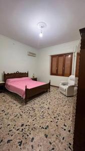 1 dormitorio con 1 cama rosa y 1 silla en Corona Apartments, en Terralba
