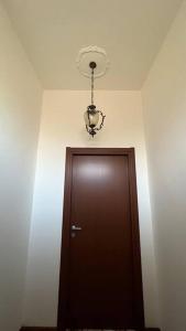 un pasillo con una puerta marrón y una lámpara de araña en Corona Apartments en Terralba