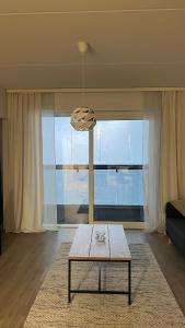 een woonkamer met een tafel en een groot raam bij Casa Emerald, laadukas kaksio saunalla, wifi, matkakeskus 280 m, juna ja bussiasema in Kajaani