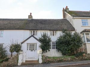een oud wit huis met een rieten dak bij Foxley Cottage in Charmouth