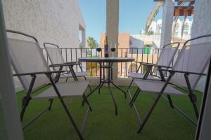 內爾哈的住宿－Sunstay PRIMERA LINEA DE PLAYA! Aptos Rio Marina，阳台上的一组椅子和一张桌子