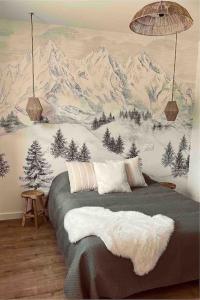 a bedroom with a bed with a mountain mural on the wall at Maisonnette avec vue Montagne et jardin in Gerde