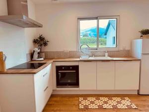 a kitchen with white cabinets and a sink and a window at Maisonnette avec vue Montagne et jardin in Gerde