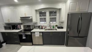 a kitchen with white cabinets and a stainless steel refrigerator at Renovated Home - Walk to Falls & Tourist District in Niagara Falls