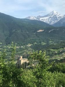 una casa su una collina con montagne sullo sfondo di Agriturismo Verger Plein Soleil a Saint-Pierre