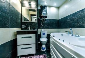 een badkamer met een bad en een toilet en een televisie bij Hotrent Bessarabka Arena in Kiev