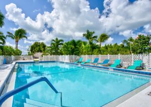 a swimming pool with blue chairs and palm trees at Bonefish Bay Motel in Marathon