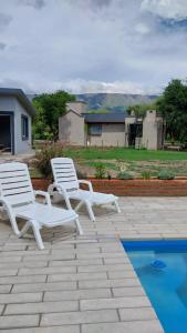 two white chairs sitting on a patio next to a pool at Cabaña Yerba Buena in Carpintería