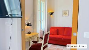 a living room with a red couch and a television at Hôtel l'Arena in Fréjus