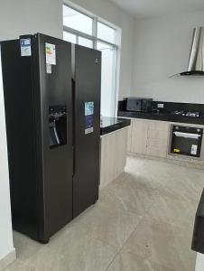 zwei schwarze Kühlschränke in einer Küche mit Mikrowelle in der Unterkunft CONDOMINIO MORAVIA 2 33 in Bujama Baja