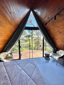 a bedroom with a bed and a large window at Pousada Cabanas Araxá in Urubici
