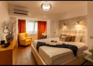 a bedroom with a large bed and a yellow chair at Downtown Oasis Unirii Apartment in Bucharest