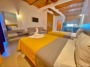 a hotel room with two beds and a bathroom at Hotel & Suites Mar y Sol Las Palmas in Rincon de Guayabitos