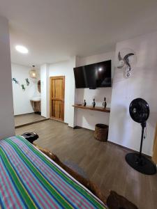 um quarto com uma cama e uma televisão de ecrã plano em Hostal Antawara Tayrona em El Zaino