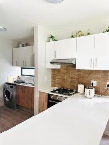 a kitchen with white cabinets and a stove top oven at Feel at Home Mbombela Self Catering in Nelspruit