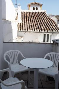 una mesa blanca y sillas en un balcón con techo en Apartamentos Los Gaitanes, en Ardales