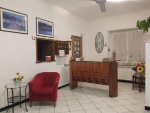 een wachtkamer met een rode stoel en een klok bij Hotel San Paolo in Varazze