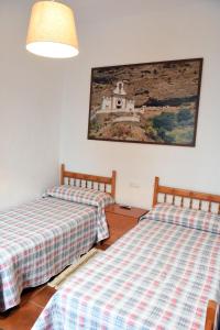 two beds in a room with a picture on the wall at Apartamentos rurales Entrecaminos in Ardales