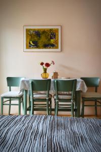 a dining room with three chairs and a table with a vase of flowers at Family Apartment Písek City Centre II. in Písek
