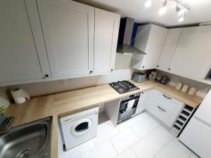 a small kitchen with white cabinets and a stove top oven at - Modern 3 Bed in Newport - Close to City Centre - in Newport