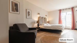 ein Schlafzimmer mit einem Bett, einem Sofa und einem Stuhl in der Unterkunft Hôtel l'Arena in Fréjus