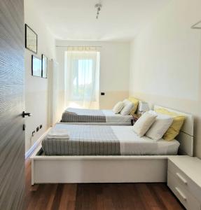 Duas camas num quarto com paredes brancas e pisos de madeira em Lavinia Apartment em La Spezia