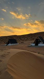 two huts in the middle of a desert at sunset at Marbella bungalows desert in Bidiyah