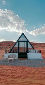 a building in the middle of the desert with two benches at Marbella bungalows desert private camp in Bidiyah