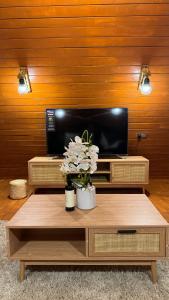 a living room with a tv and a table with flowers at Marbella bungalows desert in Bidiyah