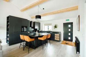 una cocina con armarios negros y taburetes naranjas en Ingleborough Lodge, en Settle