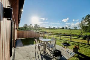 a patio with a table and chairs and a field at Ingleborough Lodge in Settle